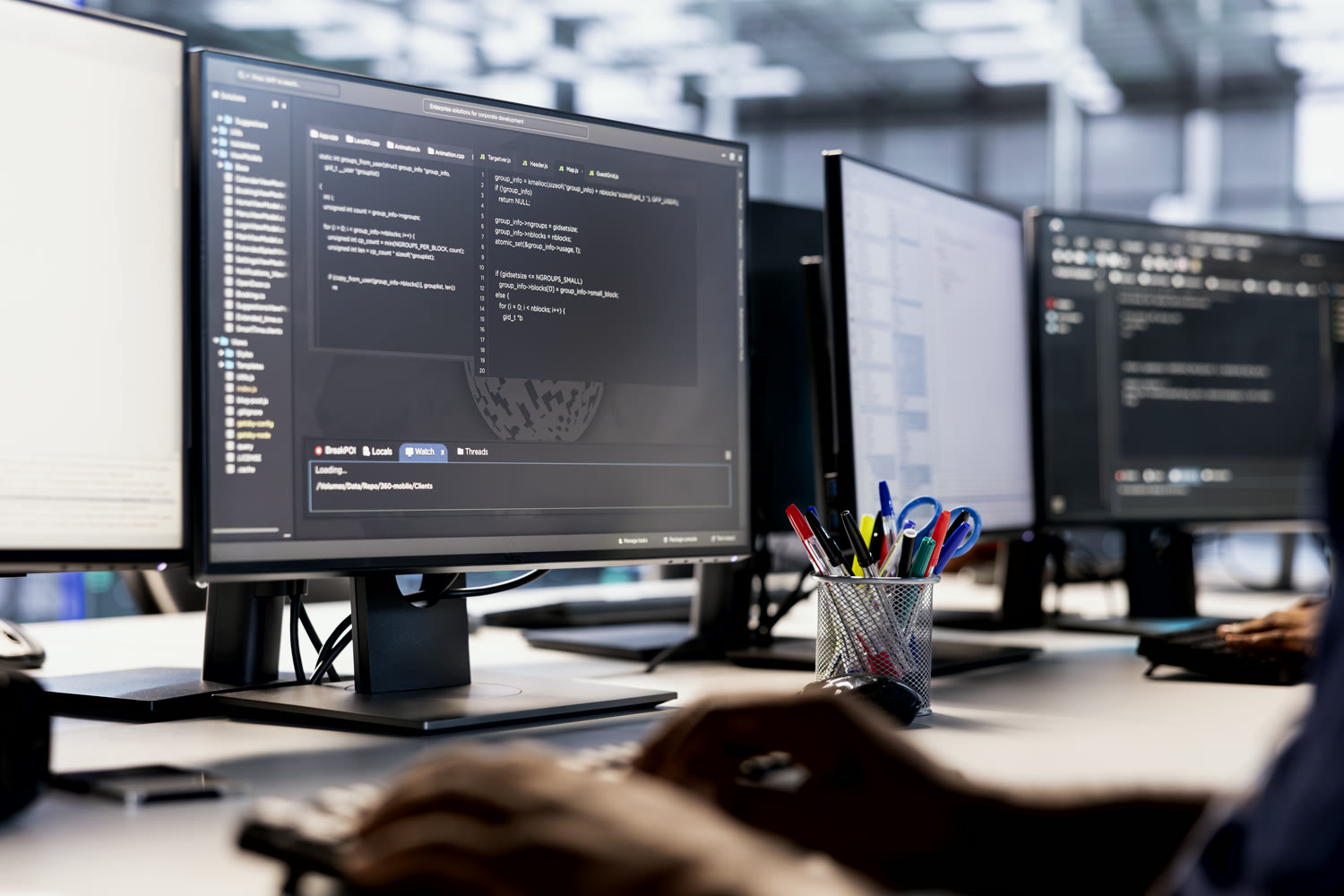 QSI Security engineers working across a multi-monitor development workstation