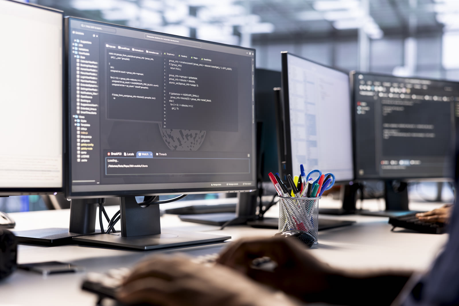QSI Security engineers working across a multi-monitor development workstation